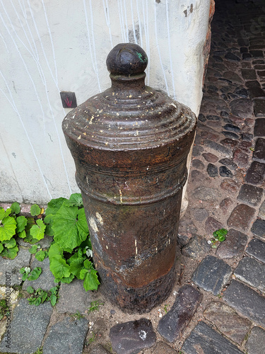 cannon barrel gun placed upside-down beside old town gates ancient vintage
