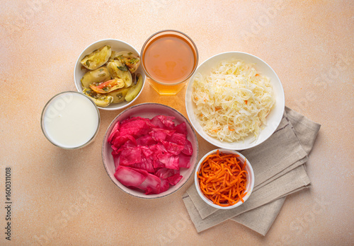 Sauerkraut, pickled cabbage, pickled cucumbers and tomatoes, fermented carrots, kefir and kombucha are arranged on a table, offering a variety of probiotic rich foods beneficial for gut health