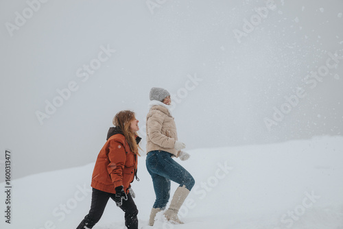 Fotografi A joyful moment of two individuals playing together in the snow, embracing winter's outdoor activities and creating lasting memories in a beautiful winter landscape