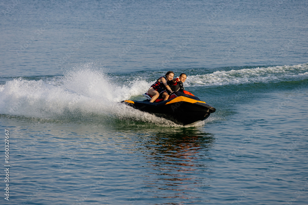 Fototapeta premium Happy couple speeding across the water on a jet ski. Concept energy, freedom, and bonding.