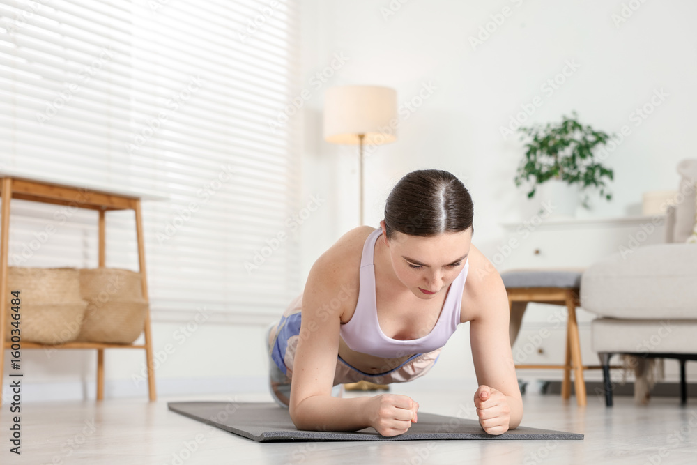 Young woman in sportswear doing plank exercise at home. Space for text Young woman in sportswear doing plank exercise at home. Space for text