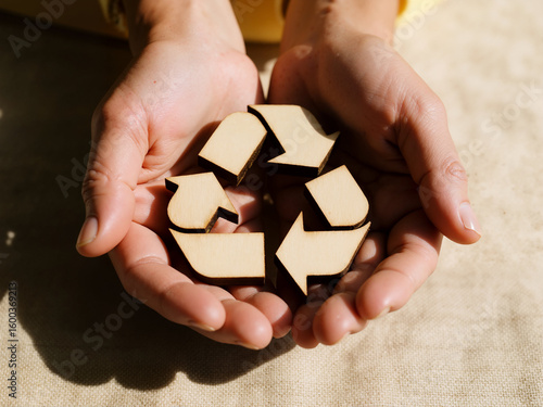 Wallpaper Mural A close-up of hands gently cradling a wooden recycling symbol, representing sustainability, environmental awareness, and eco-friendly choices in a natural setting.
 Torontodigital.ca