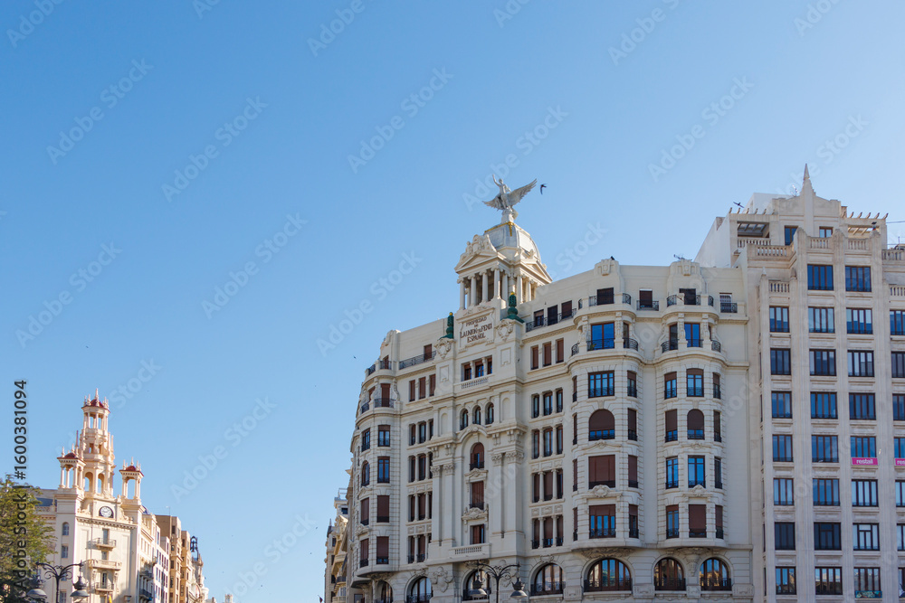 Obraz premium Beautiful architecture seen in Plaza del Ayuntamiento, featuring historic buildings with decorative facades and sculptures under a clear blue sky, ideal for urban exploration.
