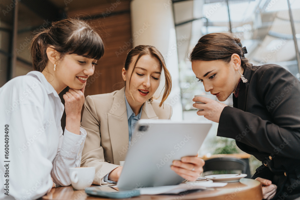 Professional women discussing ideas while using a tablet in a corporate environment Professional women discussing ideas while using a tablet in a corporate environment