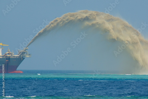 Fototapeta Trailing suction hopper dredger Prins der Nederlanden pumping sand near Vilu Island, Maldives, to counter coastal erosion caused by climate change