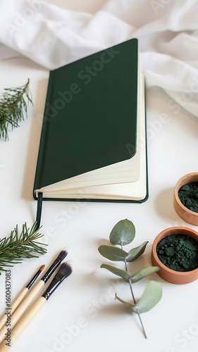 Deep green notebook with makeup brushes and green powder in bowls journal dark green