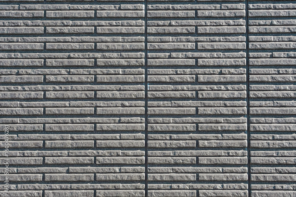 Fototapeta premium A close-up of a gray brick wall with a horizontal pattern and vertical seams.