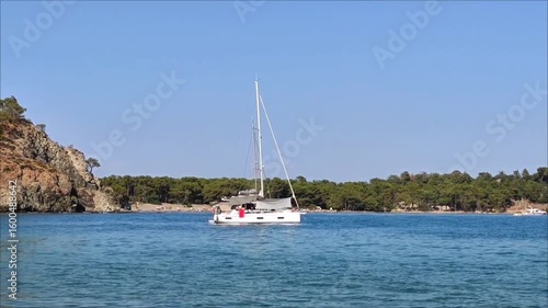 A white pleasure yacht in the blue Mediterranean sea against the backdrop of a picturesque forest place