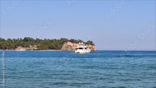 A white pleasure yacht in the blue Mediterranean sea against the backdrop of a picturesque forest place