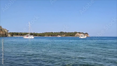 A white pleasure yacht in the blue Mediterranean sea against the backdrop of a picturesque forest place