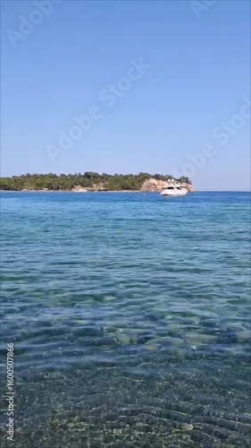 A white pleasure yacht in the blue Mediterranean sea against the backdrop of a picturesque forest place