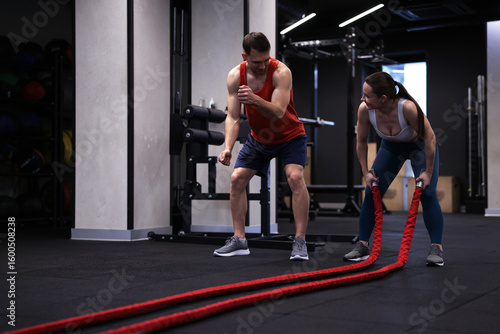 Wallpaper Mural Young woman exercising with battle ropes and professional personal trainer in gym Torontodigital.ca