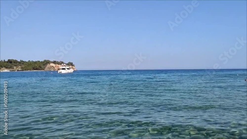 A white pleasure yacht in the blue Mediterranean sea against the backdrop of a picturesque forest place