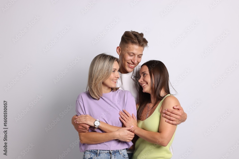 Fototapeta premium Happy friends hugging each other on grey background