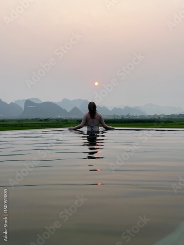 Woman in water overlooking foggy mountains