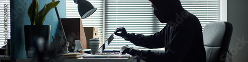 Canvas Print Header of Caucasian young man wearing black hoodie and gloves sitting at desk ha