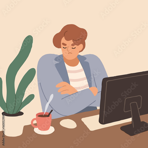 Man sitting at desk with crossed arms and frowning in office  