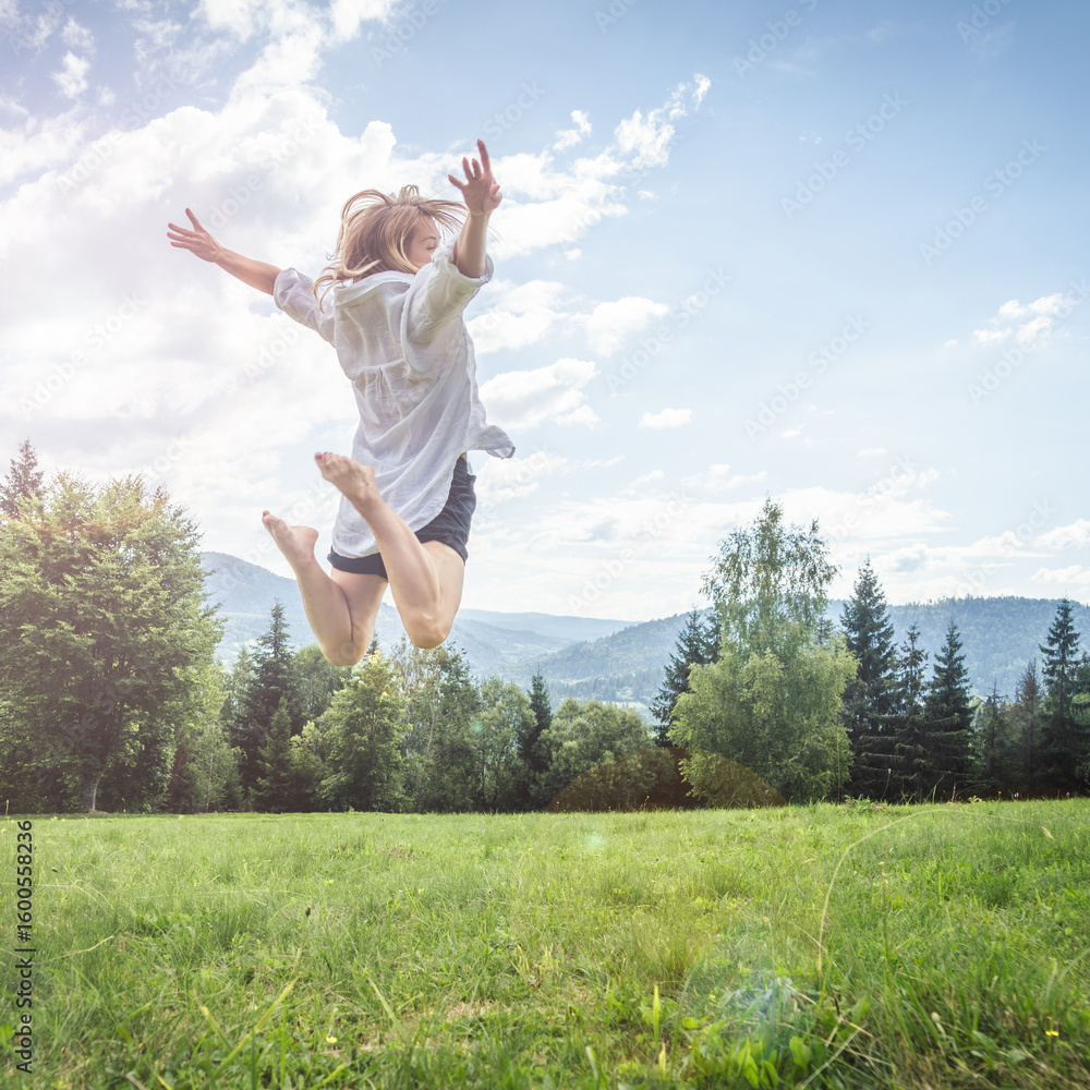 Happy young woman jumping on the meadow in mountains. Happy young woman jumping on the meadow in mountains.