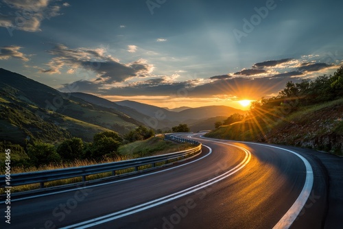 Curvy road through mountains under the sunset. Light rays pierce the clouds