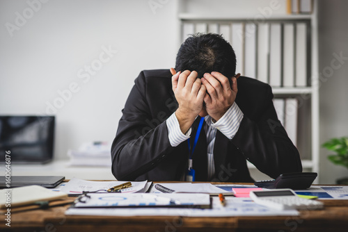 Obraz na plátně Stressed businessman sitting at his desk, his desperation and frustration, surrounded by documents and office supplies