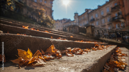 Autumn leaves scattered on stone steps, illuminated by sunlight, creating a warm and inviting atmosphere, showcasing the beauty of fall in an urban setting