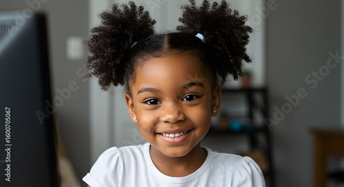 Smiling cute little african american girl with two pony tails looking at camera. Portrait of happy female child at home. Smiling face a of black 4 year old girl looking at camera with afro puff hair.