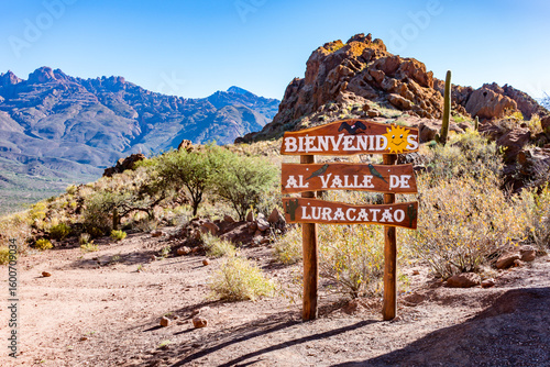 Wooden 'Welcome to Valle de Luracatao' sign amidst stunning mountain scenery in Salta, Argentina.