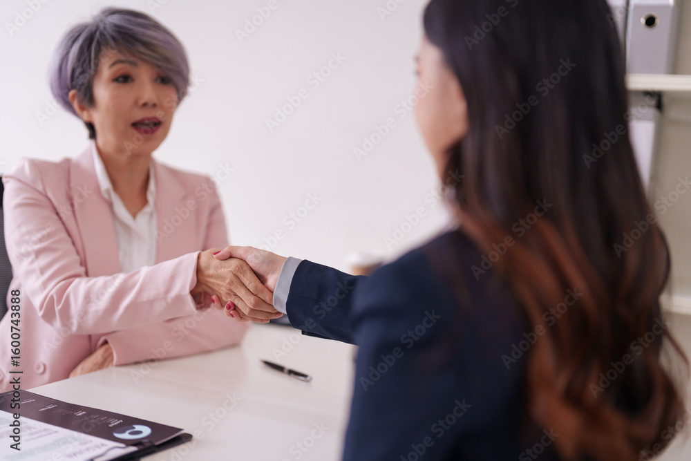 Obraz premium Asian businesswomen shaking hands during job interview or professional meeting office setting new employment agreement successful partnership discussion