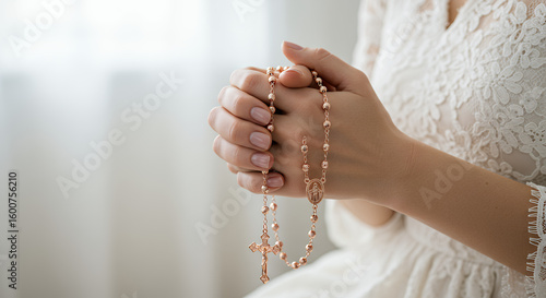 Woman in lace dress praying with a rose gold rosary in her hands, symbolizing faith and hope