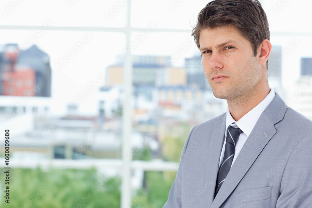 Thirty-something male standing by grid window at office wearing gray suit, striped tie, copy space Thirty-something male standing by grid window at office wearing gray suit, striped tie, copy space