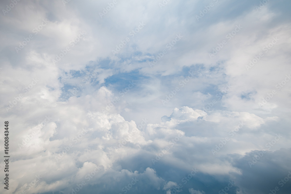Fototapeta premium White fluffy cumulus clouds float, creating the feeling of a tunnel.