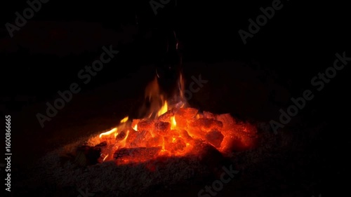 Fiery bonfire burning brightly in the darkness with glowing embers and flames
