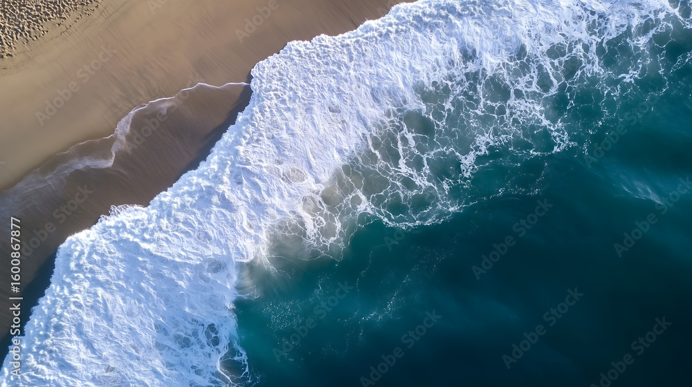 Fototapeta premium Aerial view of a beautiful sandy beach meeting powerful ocean waves, perfect for travel and nature concepts