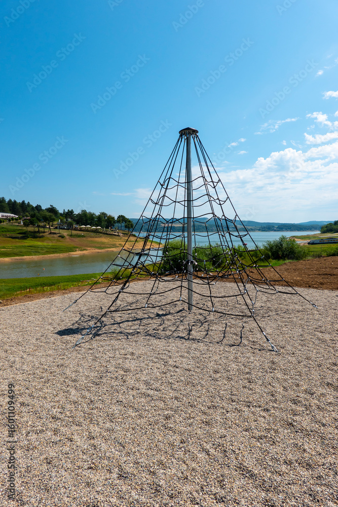 Fototapeta premium A climbing frame on a children's playground, in the background you can see the Domaša reservoir with a lack of water