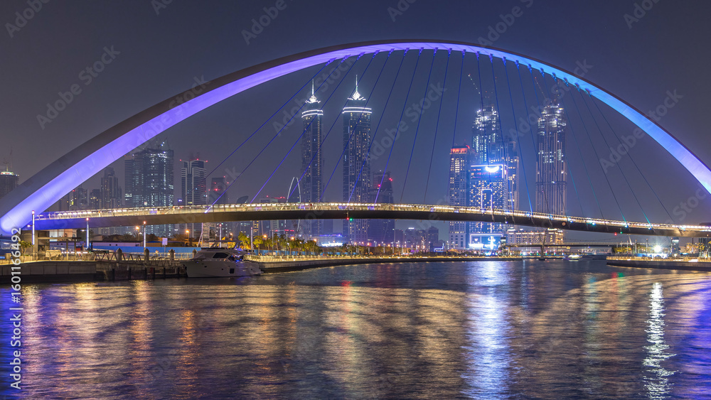 Obraz premium Futuristic Pedestrian Bridge over the Dubai Water Canal Illuminated at Night timelapse, UAE.