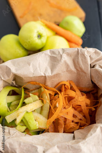 Food organic waste from apples and carrots in a paper bag for organic waste recycling. Organic waste, sorting. Environmental protection.