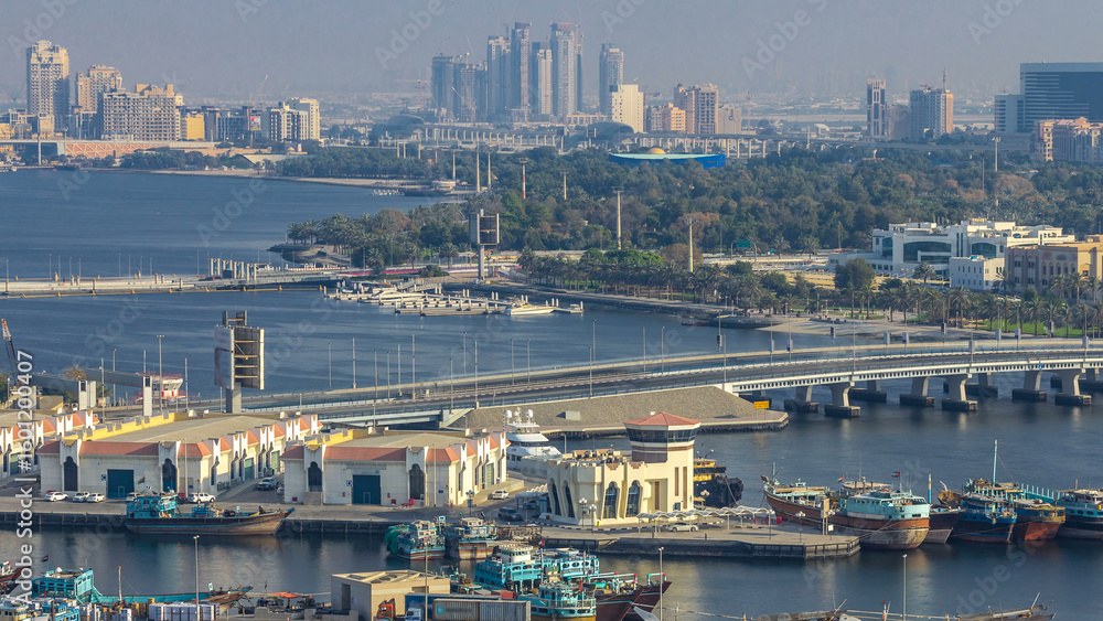 Fototapeta premium Dubai creek landscape timelapse with boats and ship in port and modern buildings in the background during sunset