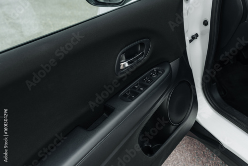 Interior close-up of Honda car door with electric window controls, speaker and handle – black panel design captured for automotive interior detailing, functionality and ergonomic layout content