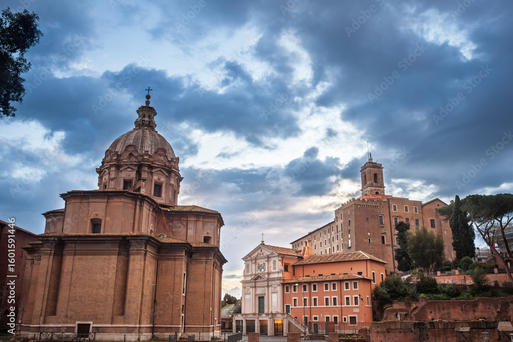 Obraz premium Soft sunset light strikes the domed church of Santi Luca e Martina and neighbouring palazzi at the edge of Rome Foro Romano, roman forum, Italy, as dramatic evening clouds roll across the sky.