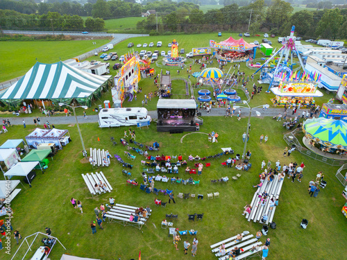 Aerial drone view of a county fair, dirt track, and a parking lot with cars. Amusement rides. Children. Fun. 