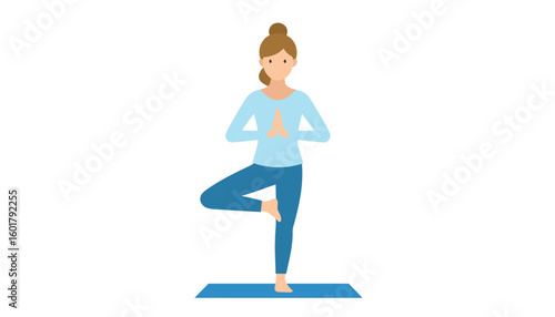 Young woman with brown hair in a bun practicing the yoga tree pose, wearing blue athletic clothing on a mat.
