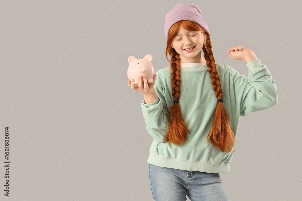 Teenage redhead girl with piggy bank on light background Teenage redhead girl with piggy bank on light background