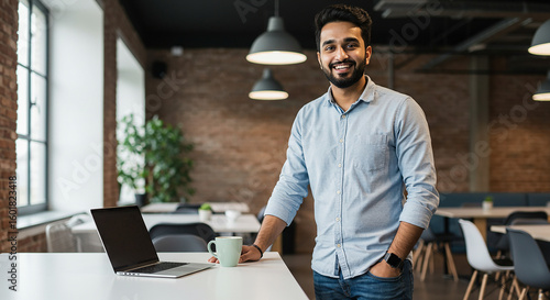 Portrait of a handsome young Indian businessman smiling confidently while standing in a modern office or co-working space