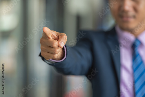 A businessman in a suit is pointing his finger at the camera.