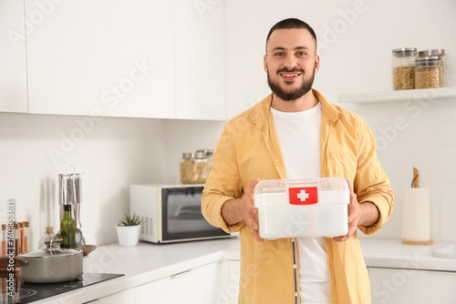 Young man with first aid kit in kitchen