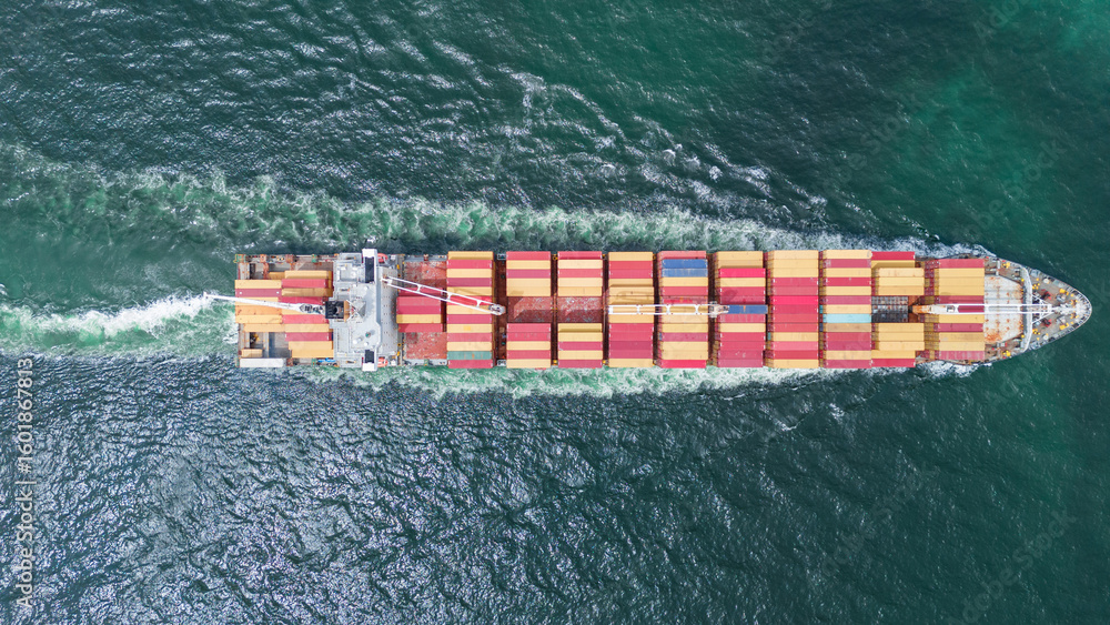 Fototapeta premium Aerial of cargo ship carrying container and running verry fast for export cargo from cargo yard port to other ocean concept smart freight shipping ship top view