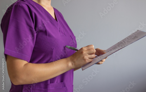 Female doctor writing medical report using pen and clipboard