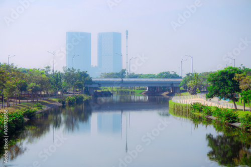 Greenbelt - PIK 2, June 26, 2025 : A calm urban river flowing past modern city buildings under a clear sky in PIK 2 Jakarta, Banten, Indonesia, ideal for cityscapes and environmental themes.