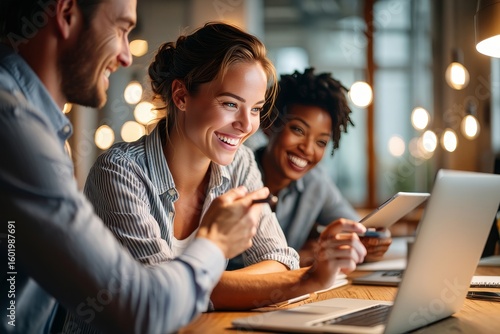 Happy diverse team working together on laptop in modern office collaboration success