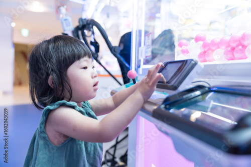 ゲームセンターのUFOキャッチャーで遊ぶ女の子の幼児